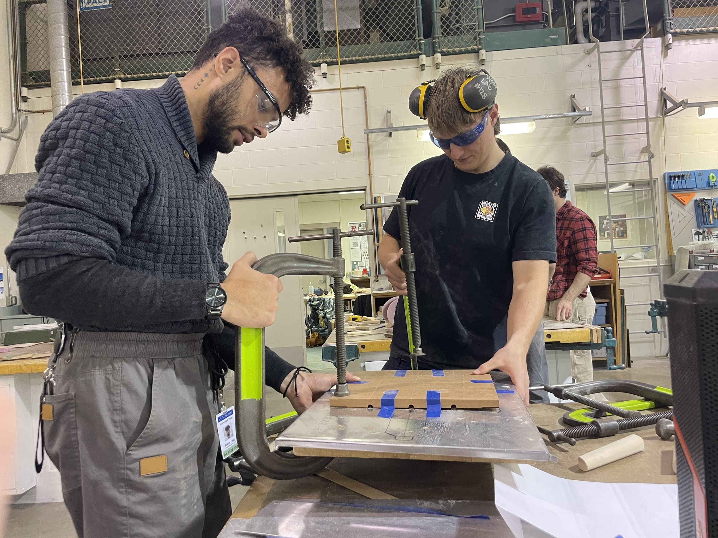 Two team members clamping sheet metal in a press